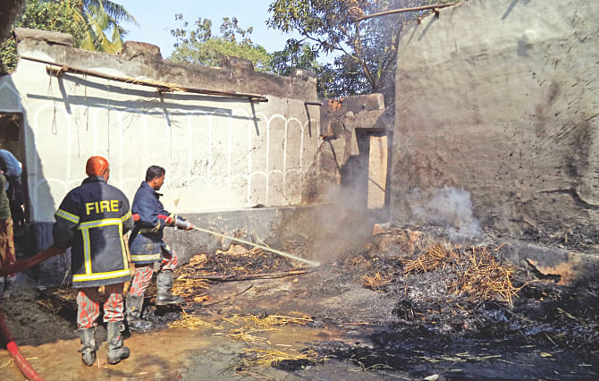 Firefighters dousing the fire at a Santal home in Parbatipur of Dinajpur yesterday following a clash between the Santals and Bangalees over the ownership of a piece of land. Photo: Star