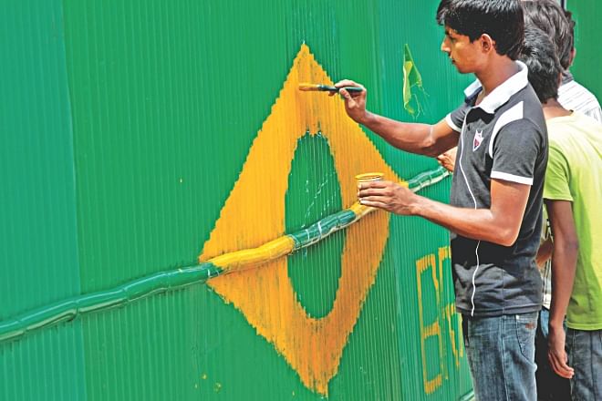 A football fan painting the flag of Brazil on a corrugated iron sheet fence at the capital's Ahmedbagh in Sabujbagh as the nation prepares for the World Cup. Photo: Sk Enamul Haq