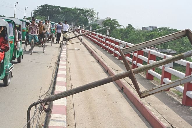 Lamp posts rest on the guard rails of Shahjalal Bridge in Sylhet yesterday. A four-minute storm early yesterday left almost 90 percent of the district in the dark. Photo: Star 