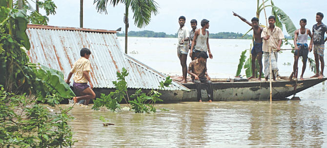 A home is being dismantled, put on a boat and moved to dry land at Char Gobordhan in Aditmari of Nilphamari yesterday. Photo: Star