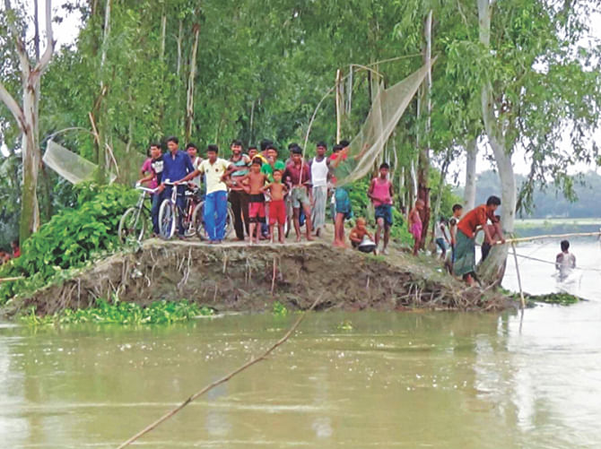 People stand on what is left of the dyke in Boirati village under Kaliganj upazila in the district. Boirati and two other villages got flooded as part of the dyke was washed away by the Teesta river yesterday afternoon. Photo: Star