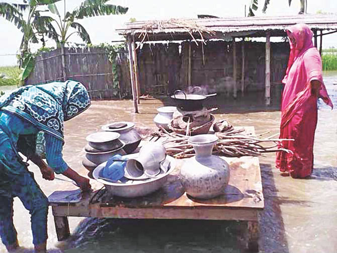 Two women cook in their front yard in ankle-deep water as the flooding and erosion by the Jamuna continue to devastate the Phulchhari upazila of Gaibandha. The photo was taken yesterday at Paglar Char. Photo: Star