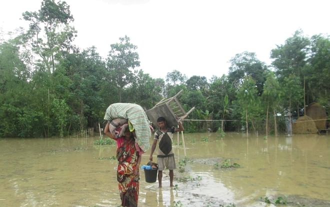 Members of a flood-affected family of Kamalganj upazila under Moulvibazar district move to a safer place yesterday. Floods triggered by days-long downpour and onrush of water from the hills across the Indian border have affected large areas in the district. PHOTO: STAR