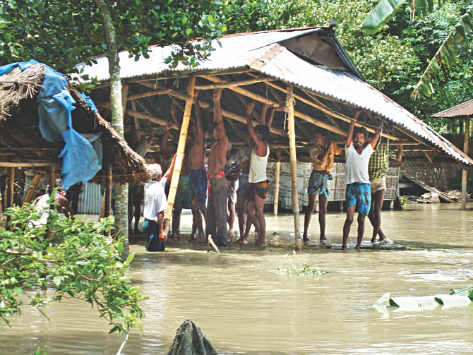 People dismantle their home in Dewabari of Hatibandha in Lalmonirhat yesterday to take it to a safer place as the over-flowing Teesta floods a large portion of the north.  Photo: Dilip Roy