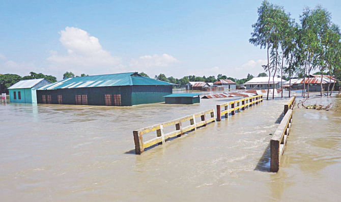 A bridge and a partially collapsed school under flood water in Islampur of Jamalpur yesterday. Several educational institutions of the district had to be closed due to the floods. Photo: Banglar Chokh