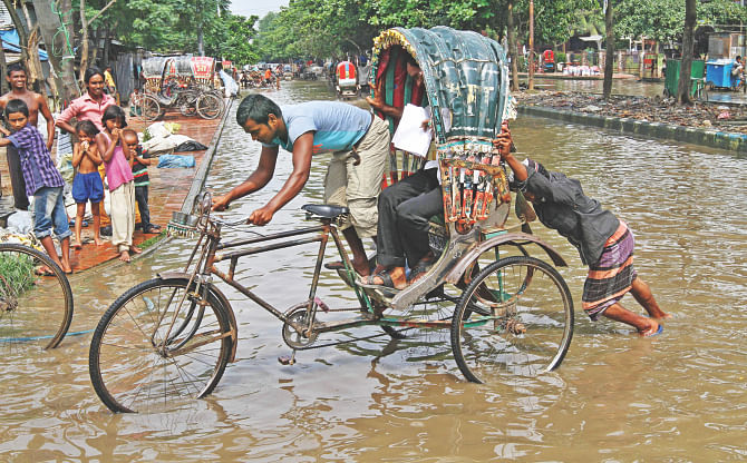 A passenger holds the handlebar while the rickshaw puller pushes the vehicle in ankle-deep water at Agargaon in the capital yesterday. The street has been under water for over a week and no government agency has done anything about it.  Photo: Amran Hossain 