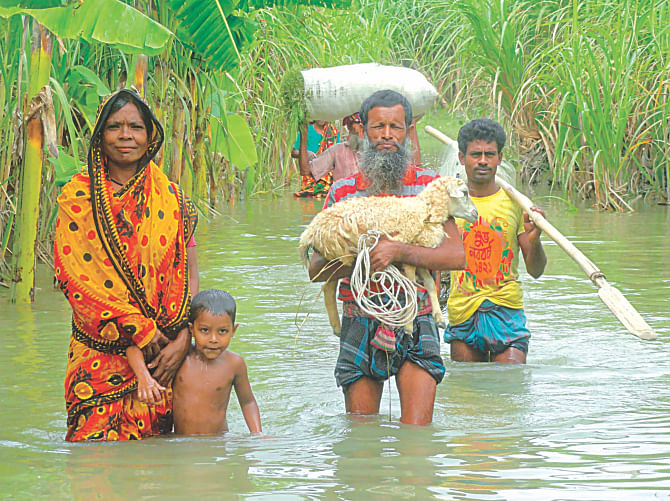 A family with their precious belongings moving to higher grounds wading through over knee-deep water at Char Shiberkuti in Lalmonirhat yesterday as flooding in the north continues to cause sufferings. Photo: Star