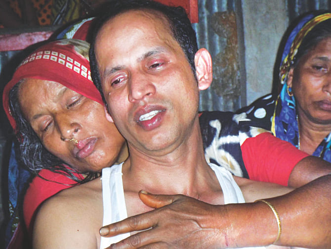 Malaysia expatriate Mozibor Rahman in shock as relatives try to comfort him yesterday. His wife and three daughters were burnt to death in Tangail allegedly for refusing a proposal for his elder daughter. Photo: Mirza Shakil