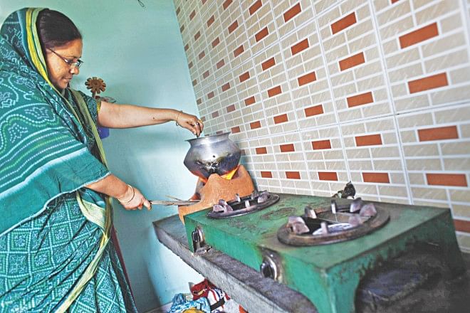 A homemaker cooks lunch on a wood-burning stove placed next to her gas-burning stoves in her kitchen in Mir Hazaribagh of Nobinagar in Demra in the capital. Titas blames the season for gas supply disruption, but many say that power plants and fertiliser factories leave too little gas for households. Photo: Rashed Shumon