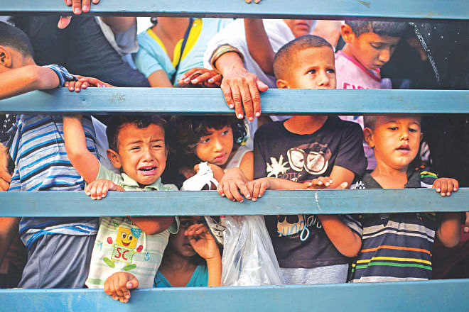 Palestinian children stand in the back of a truck as families leave their neighborhoods for safer locations amid continuing Israeli bombardment of Gaza yesterday.  Photo: AFP