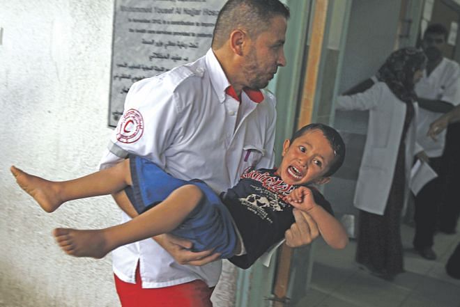 A member of the Palestinian Red Crescent Society carries an injured child at a hospital in Rafah, in the southern Gaza Strip, following an Israeli air strike before a five-hour truce went into effect yesterday. The UN in a statement has said that 80% of the Palestinian population killed so far were civilians and a major portion of the casualties were children. Photo: AFP