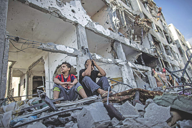 Palestinian brothers sit on the rubble of their house in front of an apartment block in part of the northern Beit Hanun district of the Gaza Strip after a 72-hour truce accepted by Israel and Hamas came into effect yesterday.     Photo: AFP