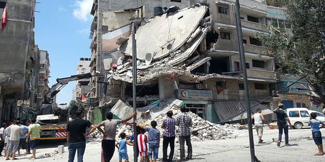 People in Gaza City look at a building destroyed by an Israeli air strike, 19 July. Photo: BBC 