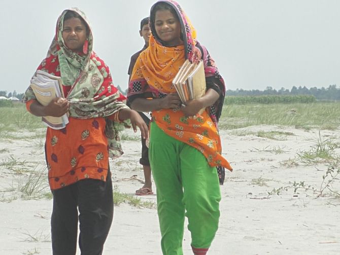 Two girls of Teesta Char village Narsingh of Aditmari upazila in Lalmonirhat go to high school for studying in the mainland every day, as their parents now understand the value of education. Photo: Star