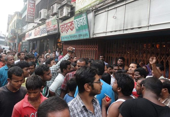 People gather in front of Faruk Jewellery at Chawkbazar in Dinajpur town as three women customers were beaten and confined there on suspicion of stealing a gold chain.  PHOTO: STAR