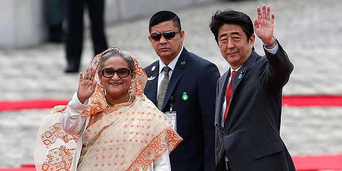 Prime Minister Sheikh Hasina (L) waves to children with Japan's Prime Minister Shinzo Abe (R) during a welcome ceremony at the state guest house in Tokyo on Monday. Photo: Reuters