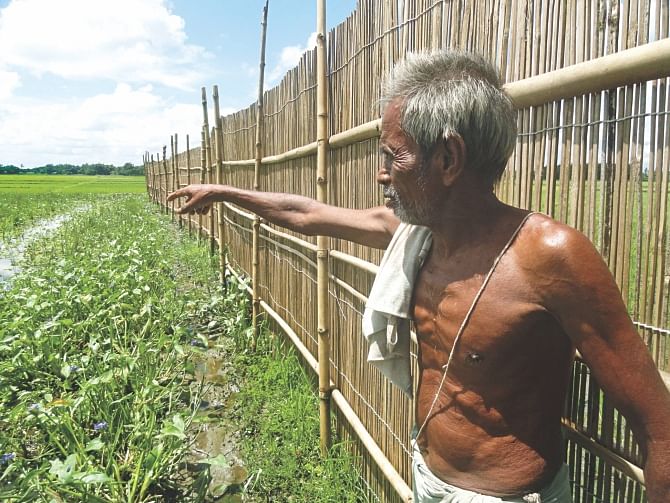 A Hindu farmer points to his land, which is being used illegally by some BNP men for fish farming in Dulali Beel of Lalmonirhat's Aditmari upazila. Photo: Star