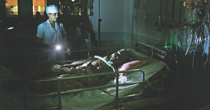 With the torch of her mobile phone a nurse checks up on a patient at the High Dependency Unit of Dhaka Medical College Hospital yesterday evening. The blackout left the unit with no lights and air conditioning. Key lifesaving equipment were running with generator backup.  Photo: Palash Khan