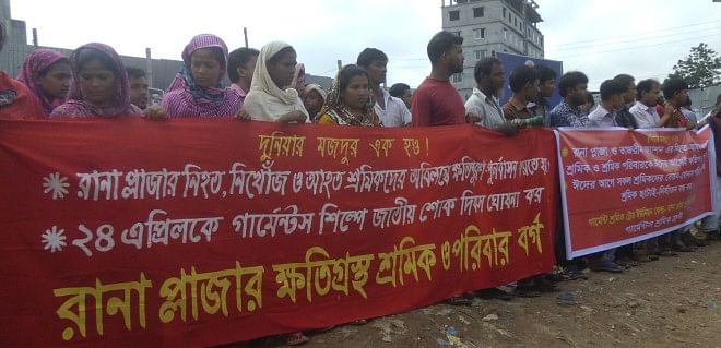 Victim families of Rana Plaza collapse form a human chain on the site in Savar, outside the capital, yesterday demanding compensation for those who lost their lives, sustained injuries and went missing in the nine-storey building collapse on April 24 last year.  Photo: Star