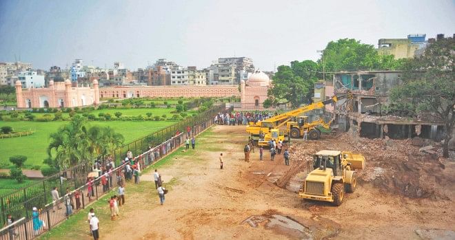Two bulldozers and a crane knocking down a building illegally built on the northwest part of Lalbagh Fort in the capital yesterday. The Department of Archaeology finally succeeded in getting one of the illegal buildings demolished through its relentless efforts since 2009.   Photo: Star