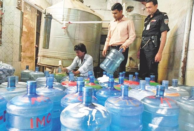 Executive Magistrate Anwar Pasha, centre, during a drive in the capital's Tejgaon yesterday to seal off three unauthorised drinking water supplying factories which used to fill jars with tapwater for sale. Rapid Action Battalion-2 and a Bangladesh Standards and Testing Institution representative assisted the drive. Photo: Banglar Chokh