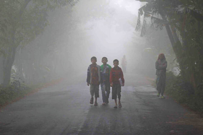 In the shivering cold three boys walk to school through dense fog on Dhaka-Barisal highway yesterday morning at Kashipur in Barisal.  Photo: Arifur Rahman