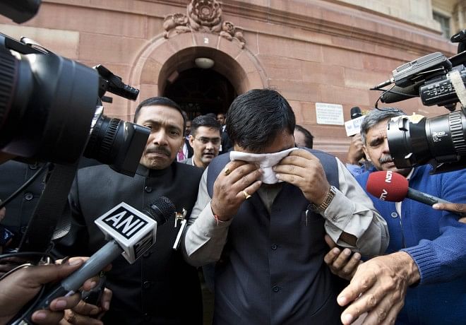 An unidentified member of India's Parliament, holding a handkerchief to his face after being affected by pepper spray, leaves parliament after protests inside the building in New Delhi, yesterday. Photo: AFP