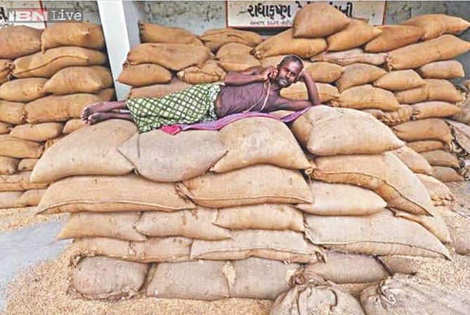 A labourer speaks on a mobile phone while lying on sacks filled with rice at the Agricultural Produce Market Committee market yard, on the outskirts of Ahmedabad. Photo: REUTERS/FILE 