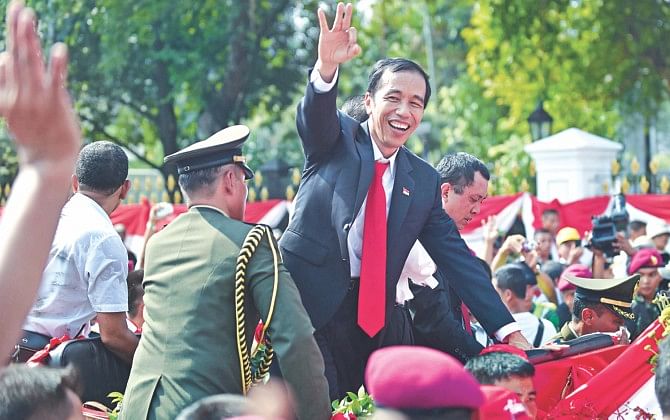 Indonesia President Joko Widodo (C) gestures from a horse drawn cart on his way to the palace after his inauguration ceremony at the House of Representatives in Jakarta yesterday. Photo: AFP
