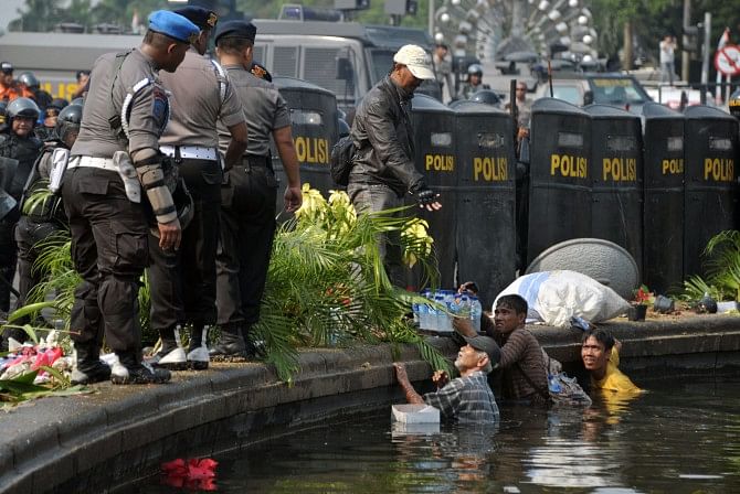 Street vendors hide in the water of a fountain during the clashes with police. Photo: AFP