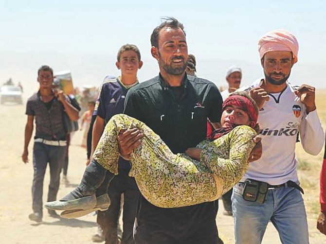 A Yazidi man helps an injured woman while fleeing a mountain besieged by jihadists in northern Iraq on Saturday.  Photo: AFP