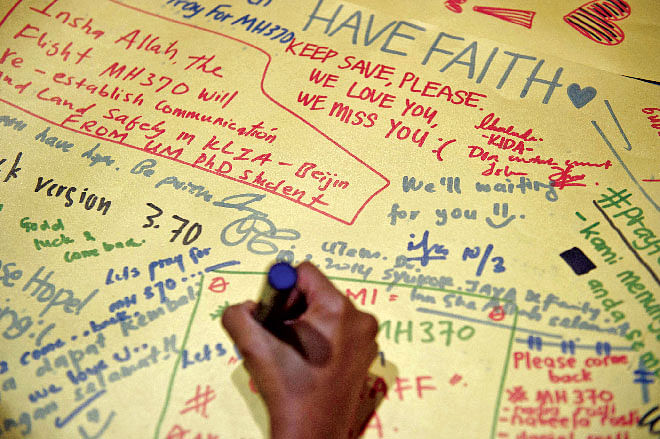 A man writes on a poster carrying messages for the passengers of the missing Malaysia Airlines plane at the Kuala Lumpur International Airport. Photo: AFP