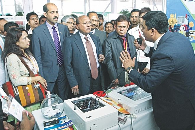 Tofail Ahmed, commerce minister, looks on as a stall attendant demonstrates the functions of a TYY-branded fire alarm system at the International Trade Expo for Building and Fire Safety at Sonargaon Hotel in Dhaka yesterday. The system, locally marketed by ZM International, is equipped to detect the source of smoke, fire or heat and issue timely warnings. Atiqul Islam, president of BGMEA, was also present.  Photo: Star