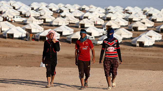 Displaced people from the minority Yazidi sect, who fled the violence in the Iraqi town of Sinjar, walk in Bajed Kadal refugee camp south west of Dohuk province August 15. Photo: Reuters 