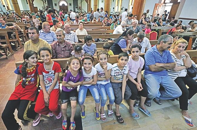 Iraqi Christians who fled the violence in the village of Qaraqush sit in Saint-Joseph church in the Kurdish city of Arbil, in Iraq's autonomous Kurdistan region, after their arrival, yesterday.  Photo: AFP