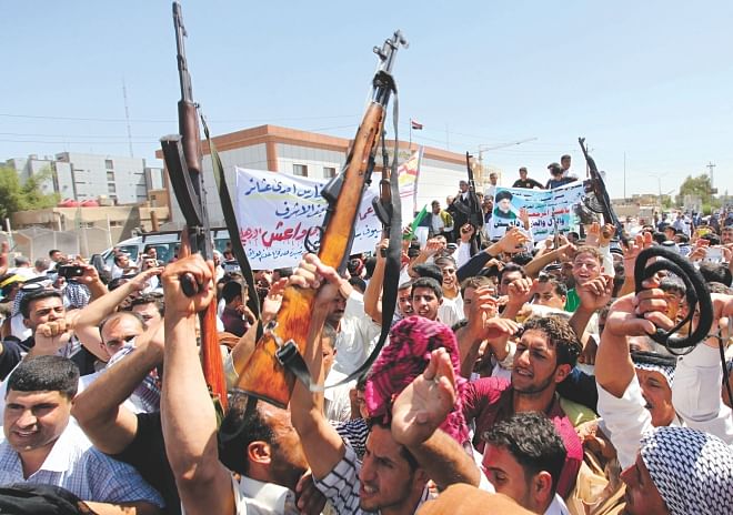 Iraqi men raise up weapons and shout slogans yesterday as they demonstration in the central Shia Muslim shrine city of Najaf to show their support for the call to arms by Shia cleric Grand Ayatollah Ali al-Sistani. Photo: AFP