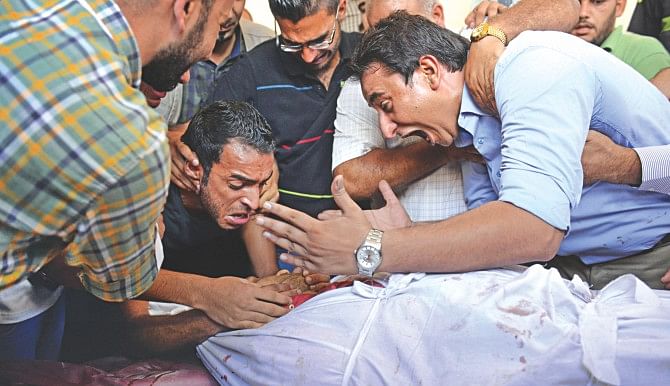Family and friends mourn over the body of a Palestinian translator, Ali Abu Afash, that was killed in Beit Lahiya in the northern Gaza strip yesterday. An Italian cameraman working for international news agency Associated Press was among at least five people killed in northern Gaza as explosives experts were dismantling an Israeli missile.  Photo: AFP