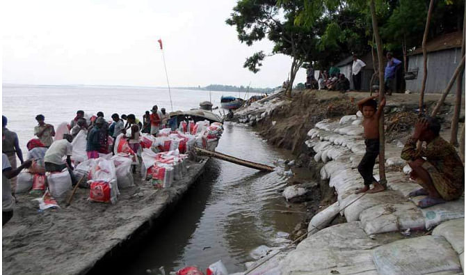 Workers of Water Development Board set sandbags on the bank of the Jamuna at Kamarpara village in Phulchhari upazila under Gaibandha district to save the area from the fury of the turbulent river that devoured 60 homesteads within a couple of hours early yesterday. PHOTO: STAR