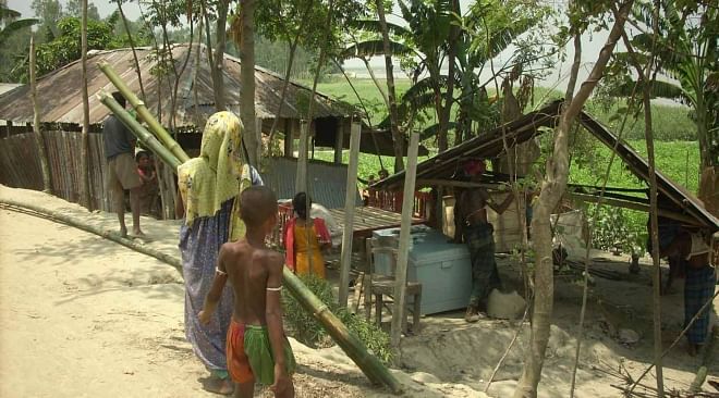 Faced with erosion by the Jamuna, a family at Nijkornipara village in Kutubpur union of Sariakandi upazila under Bogra district carries the separated parts of their house to a safer place on Saturday. PHOTO: STAR