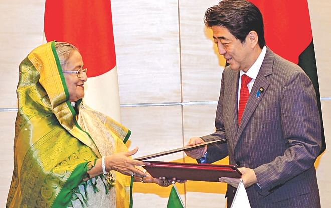 Prime Minister Sheikh Hasina and Japanese PM Shinzo Abe sign and exchange a joint statement at the latter's office in Tokyo yesterday.  Photo: BSS