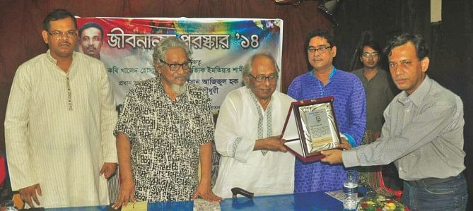 As eminent writer Hassan Azizul Haque hands over the award at the prize giving ceremony, (R) poet Asad Chowdhury looks on. Photo: Star