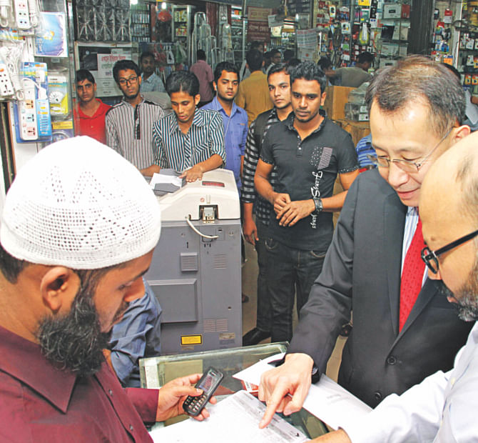 Jin-Yong Cai, chief executive officer of International Finance Corporation, visits a bKash agent shop in Dhaka recently. IFC, the private sector arm of the World Bank, made an equity investment in bKash in 2013. Photo: Bkash