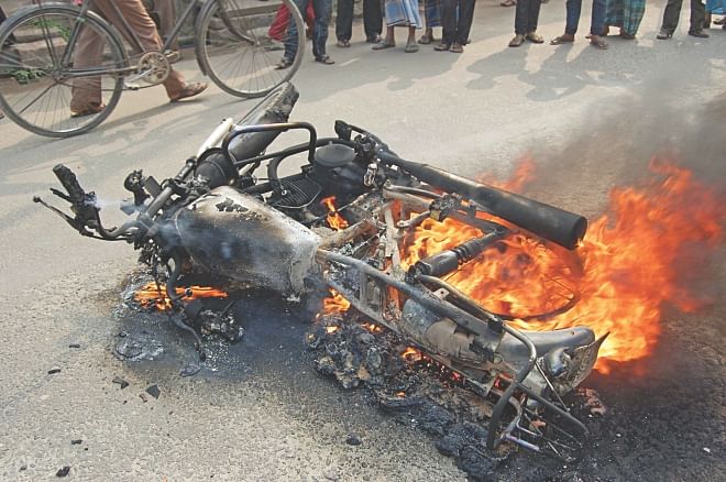 A journalist's motorbike burns in Khandar intersection area of Bogra town yesterday, the day before the national election. Activists of the main opposition BNP, which boycotts the election and is out to resist it apparently by violence, torched the vehicle though the journalist gave his identity and pleaded repeatedly not to do that. Photo: Star