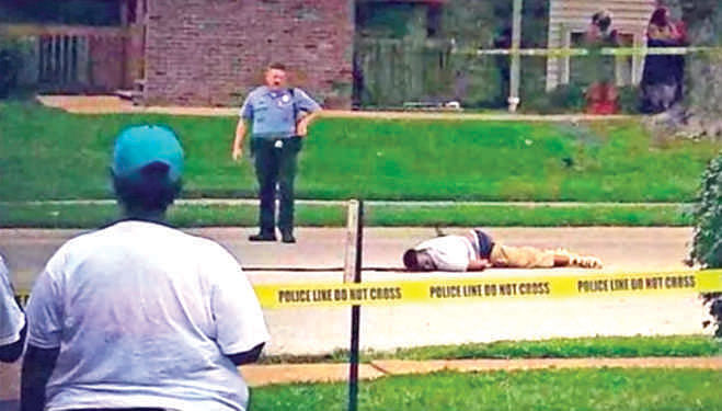 A YouTube grab shows Michael Brown bleeding after being shot by Darren Wilson; a policeman looks on.     