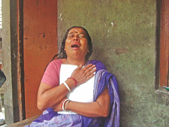 Kalpana Biswas, holding on tight to a photo of her daughter Trishna, cries her heart out at her residence in Jhenidah yesterday. Trishna was one of 11 people killed when a train rammed the bus they were travelling in at a level crossing on Friday.  Photo: Star