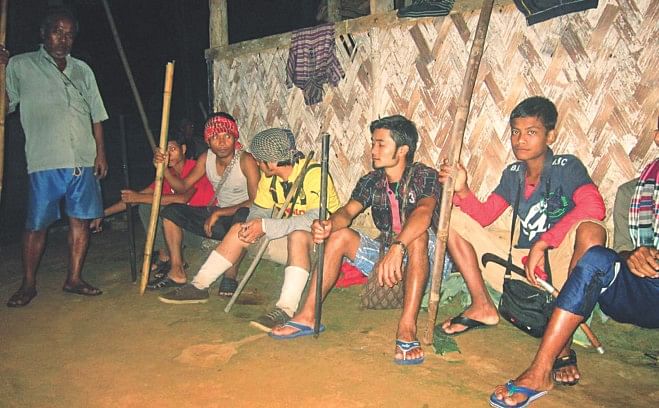 Armed with sticks, male members of the Khasi community guard their houses at Nahar Punjee-1, a hilltop village of the indigenous people, in Moulvibazar's Srimangal upazila on Friday night after Bangalee land grabbers attacked the community earlier in the day in an attempt to evict them. Photo: Mintu Deshwara