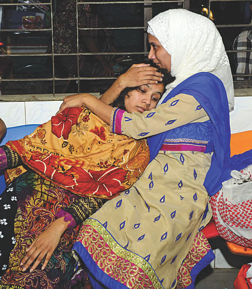 A relative tries to console Ratri, wife of deceased Simon, at Dhaka Medical College Hospital last night. Simon and his father were shot near their Khilgaon home apparently by muggers. Photo: Courtesy
