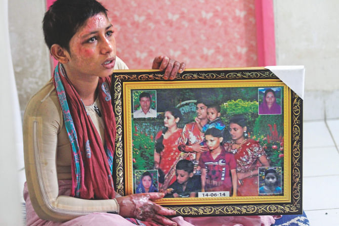 Everyone, in the photo she holds at her relative's home last week, is gone. Her father, top left in the framed photo, died yesterday. A fire in June killed others.  Photo: Sk enamul haq