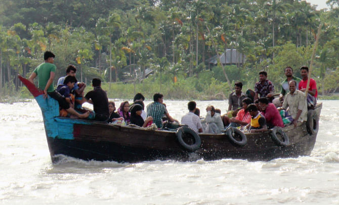 Some of the passengers take a risky ride on a small trawler to cross the mighty Meghna. PHOTO: STAR
