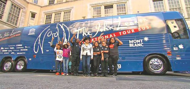 The schoolchildren pose with Ono in front of the Lennon bus. 
